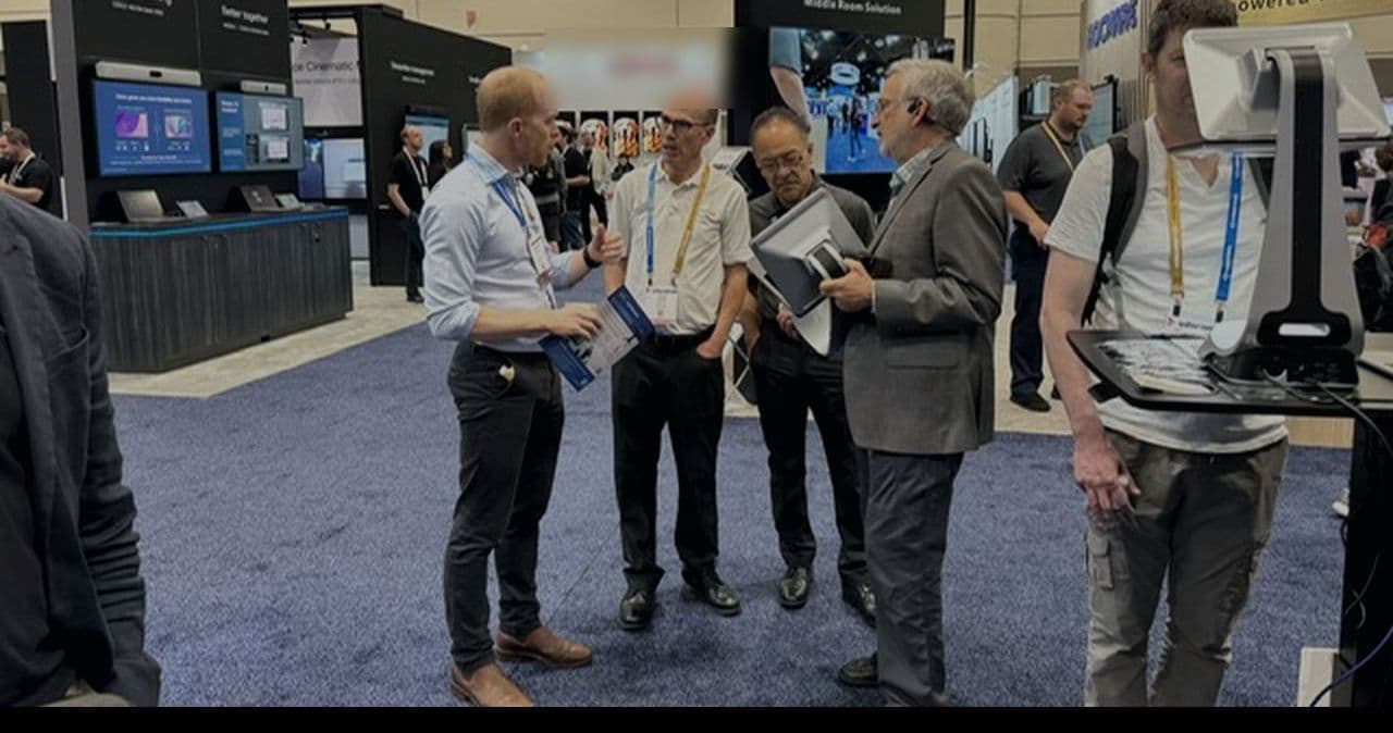 The Lumirah team talking with attendees beside an iVi on the InfoComm show floor